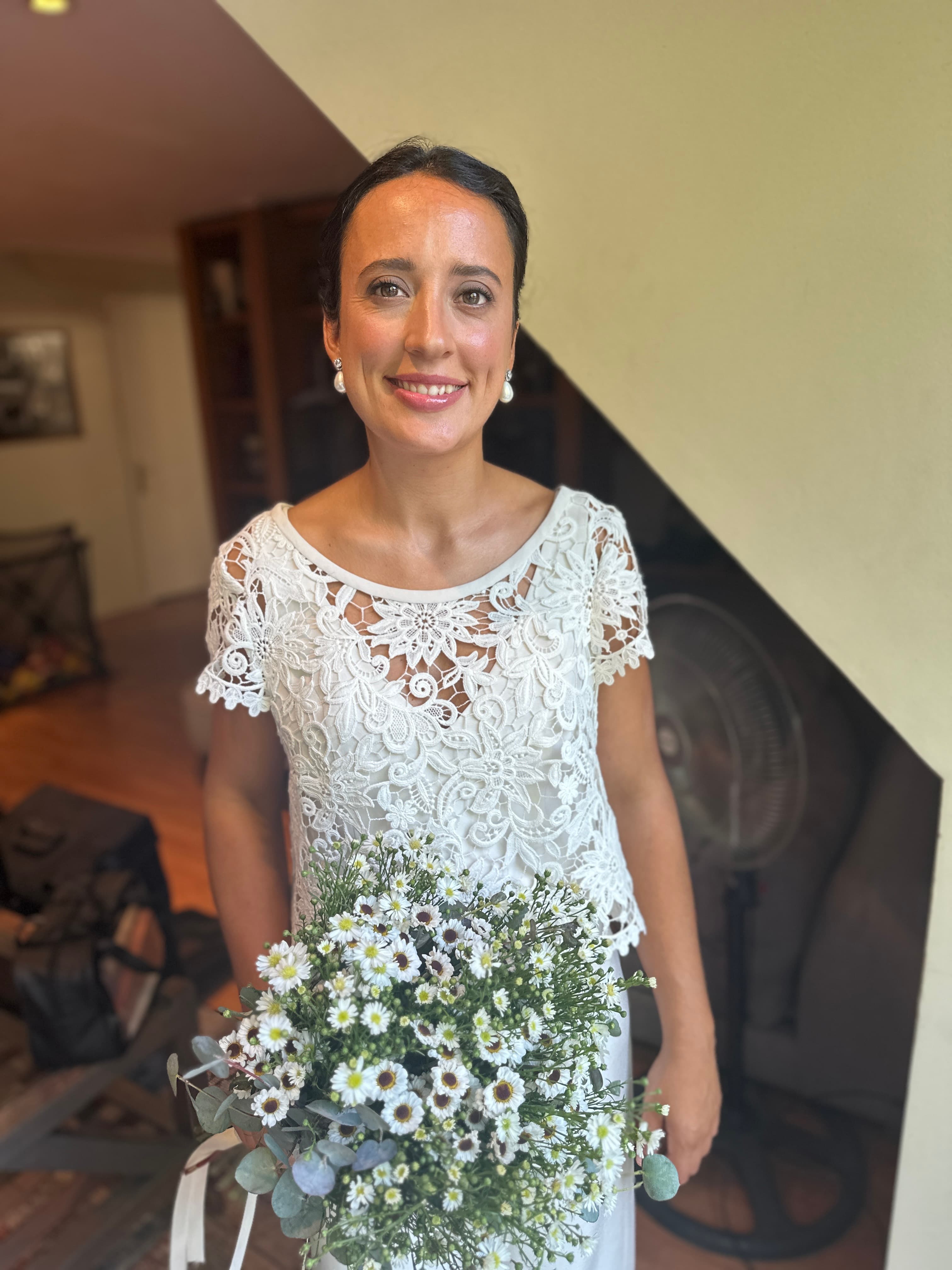 Novia civil con vestido de encaje blanco, ramo de margaritas y maquillaje suave
